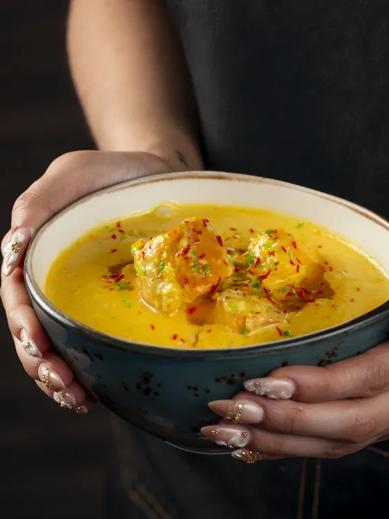A bowl of mango chicken held in both hands