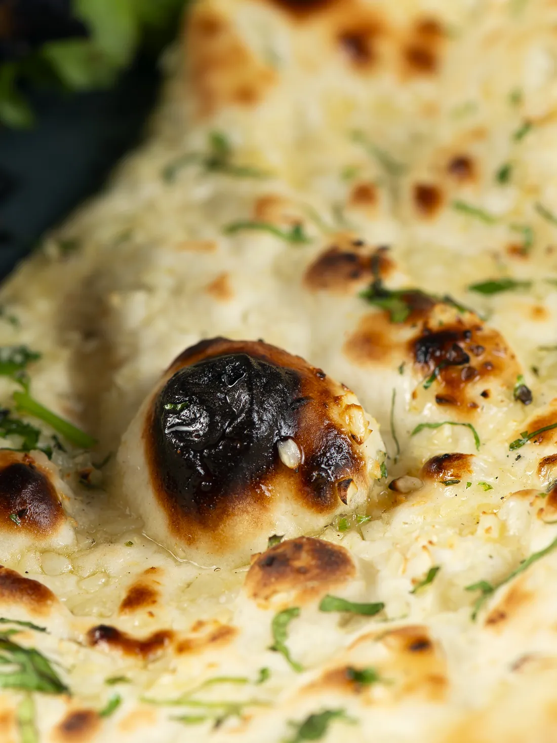 Naan charred in places, with chopped coriander on top