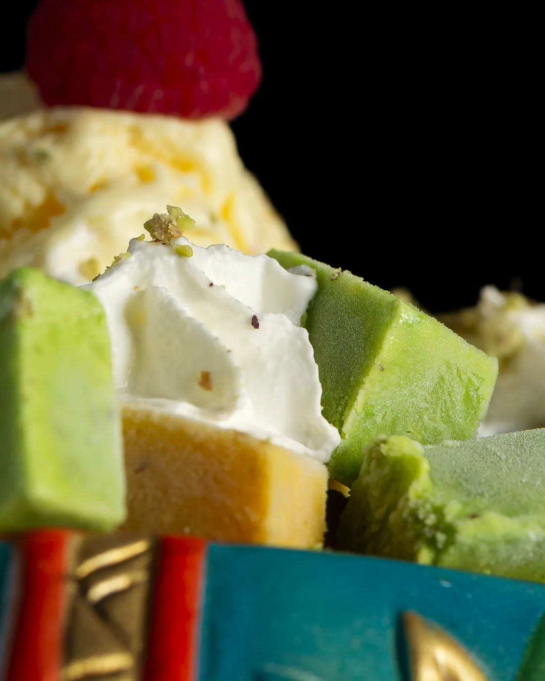 A dessert with ice cream, cream, green sweets and a raspberry, served on a ceramic elephant