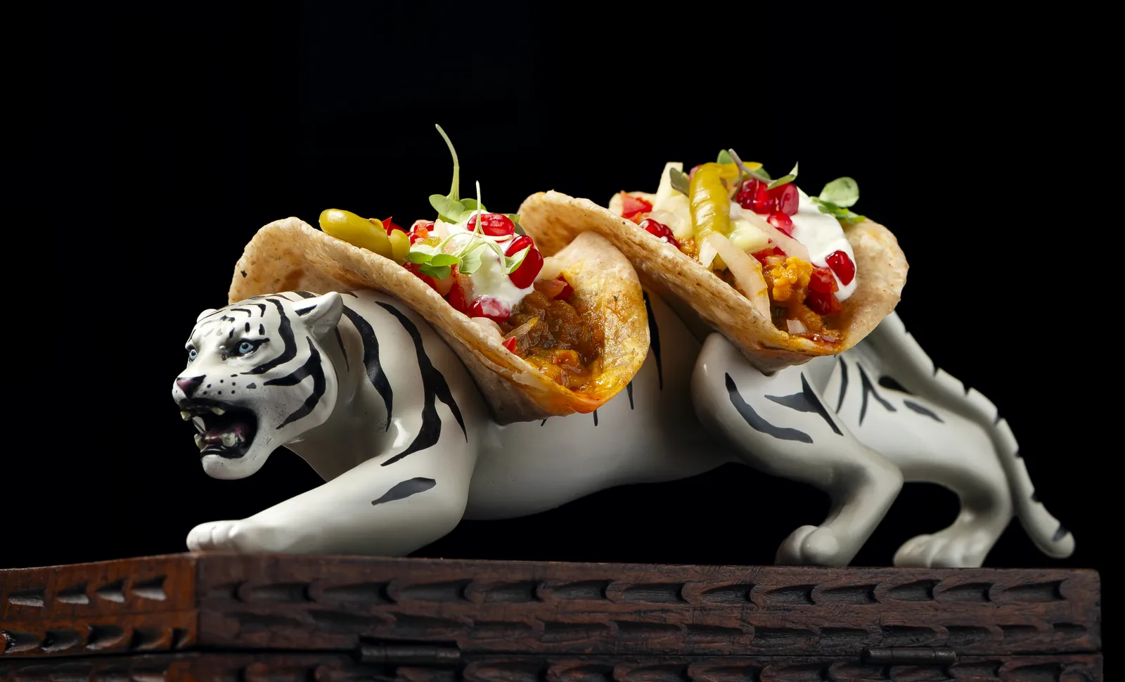 Two Tiger tacos served on the back of a white ceramic tiger