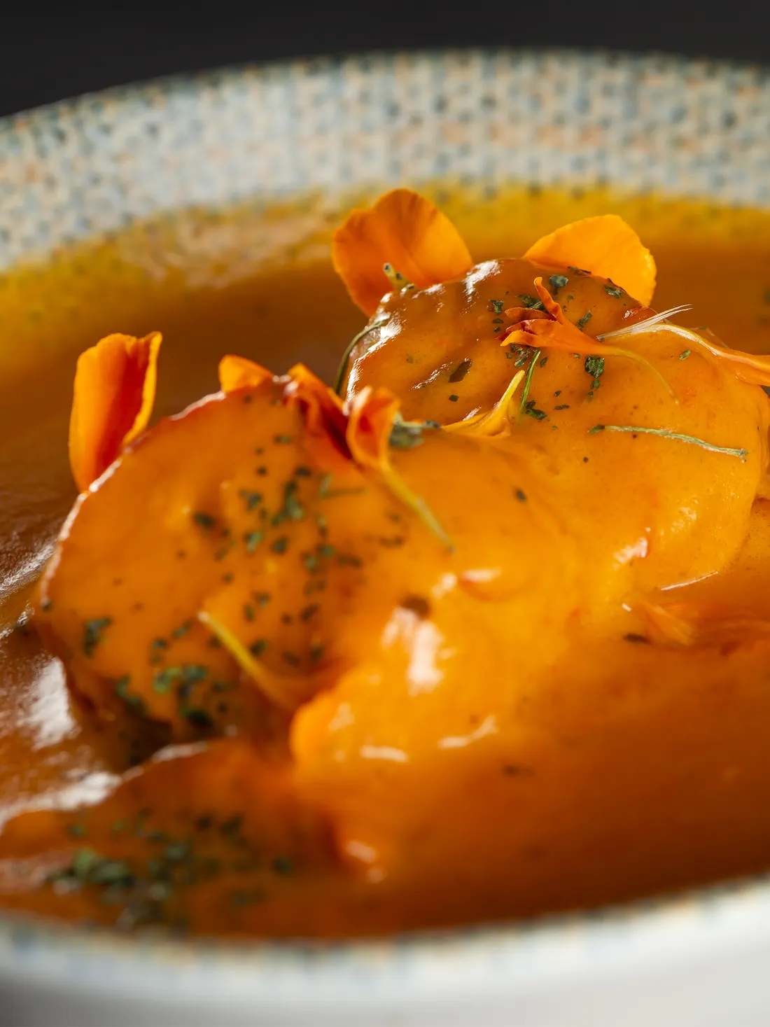 Chicken tikka masala up close, with marigold petals on top