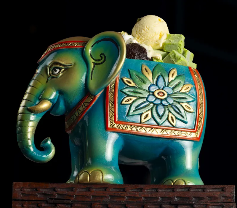 A blue ceramic elephant with an ice cream dessert on top
