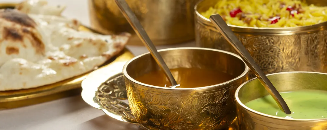 Bread, sauces and yellow rice in brass bowls and trays